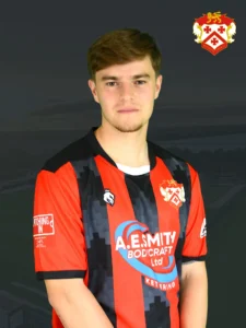 Portrait of a young man in a red-and-black striped football jersey, posed against a dark background with the club crest in the top-right corner.