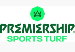 premiership_sports_turf_logo | Kettering Town FC PremierShip Sports Turf logo: green crown in a hexagon above dark green 'PREMIERSHIP' and lime green 'SPORTS TURF' text.