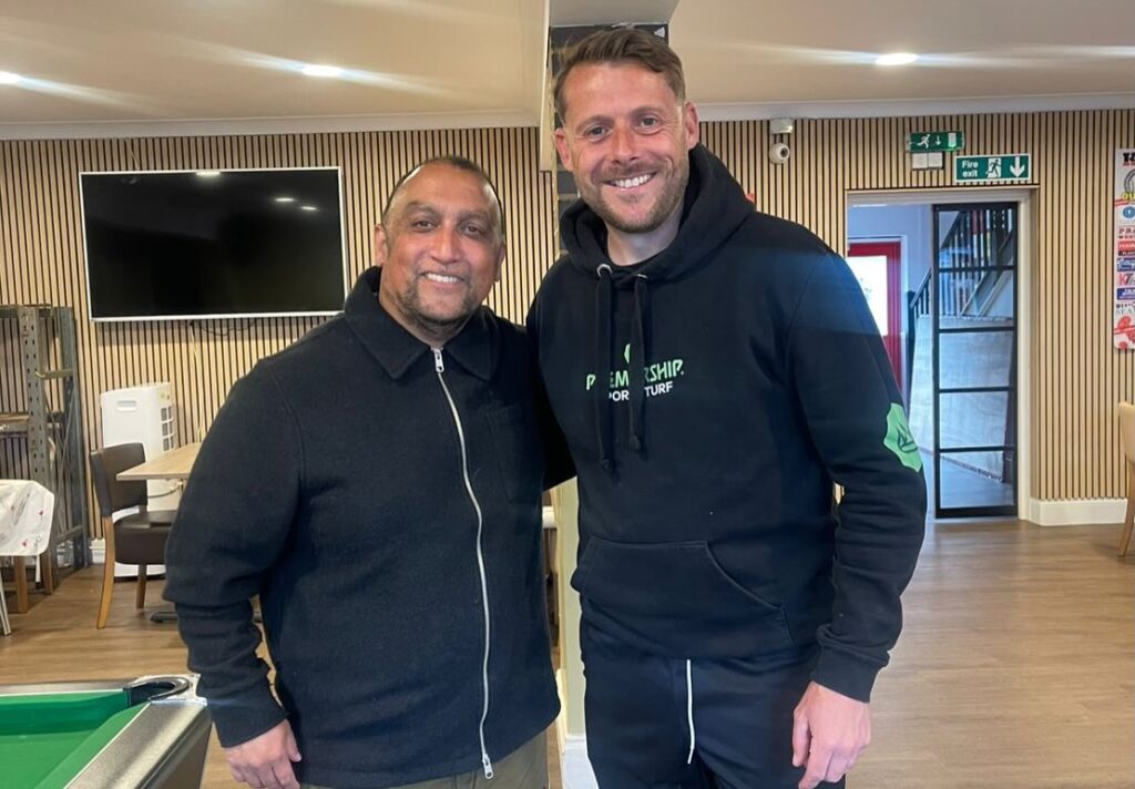 premiership_sports_turf_photo | Kettering Town FC Two men standing indoors, smiling for the photo with a pool table visible in the foreground.