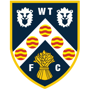 Club crest: navy shield with gold border, two white lion heads at the top, a diagonal white band with six red-and-yellow circles, and a gold wheat sheaf with the letters WTFC.